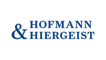 Das Logo von Hofmann & Hiergeist zeigt den Firmennamen in blauer, großgeschriebener Serifenschrift. Das Et-Zeichen ist ebenfalls blau und im Einklang mit dem Text gestaltet, zentriert zwischen den Namen. Das Gesamtdesign wirkt professionell und minimalistisch.